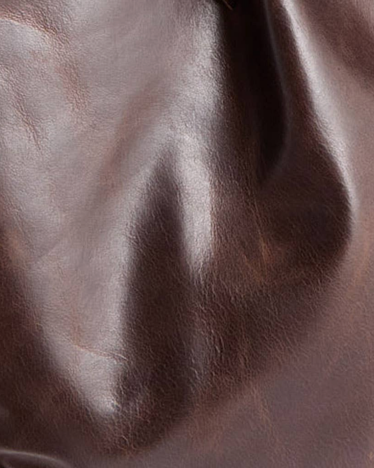 Close-up of dark brown leather texture on a Birdie by Nina Liddle Design Pinched Bottom Traveler small handbag.