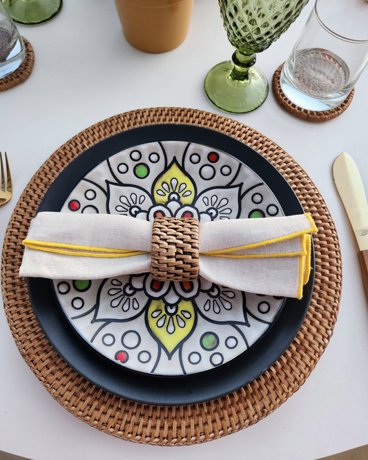 Birdie by Nina Liddle Design handwoven rattan charger plate under a patterned ceramic plate with a linen napkin