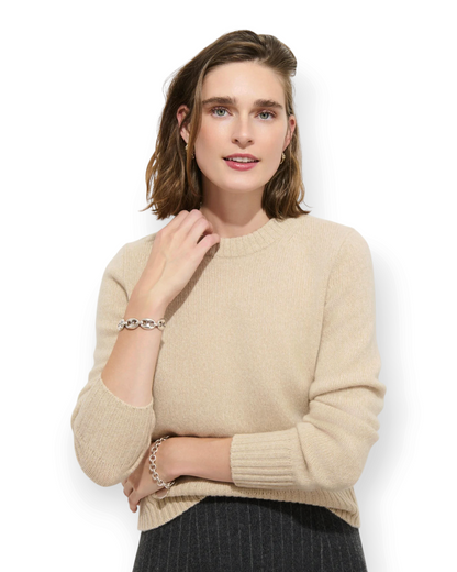 Model wearing a Birdie by Nina Liddle Design beige washed cashmere crewneck sweater with ribbed cuffs.