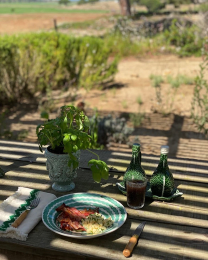 Birdie by Nina Liddle Design green squiggle ceramic dinner plate set on a rustic outdoor table with breakfast