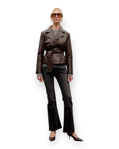 Birdie by Nina Liddle Design brown lambskin leather belted jacket with notched lapels worn by a model in sunglasses
