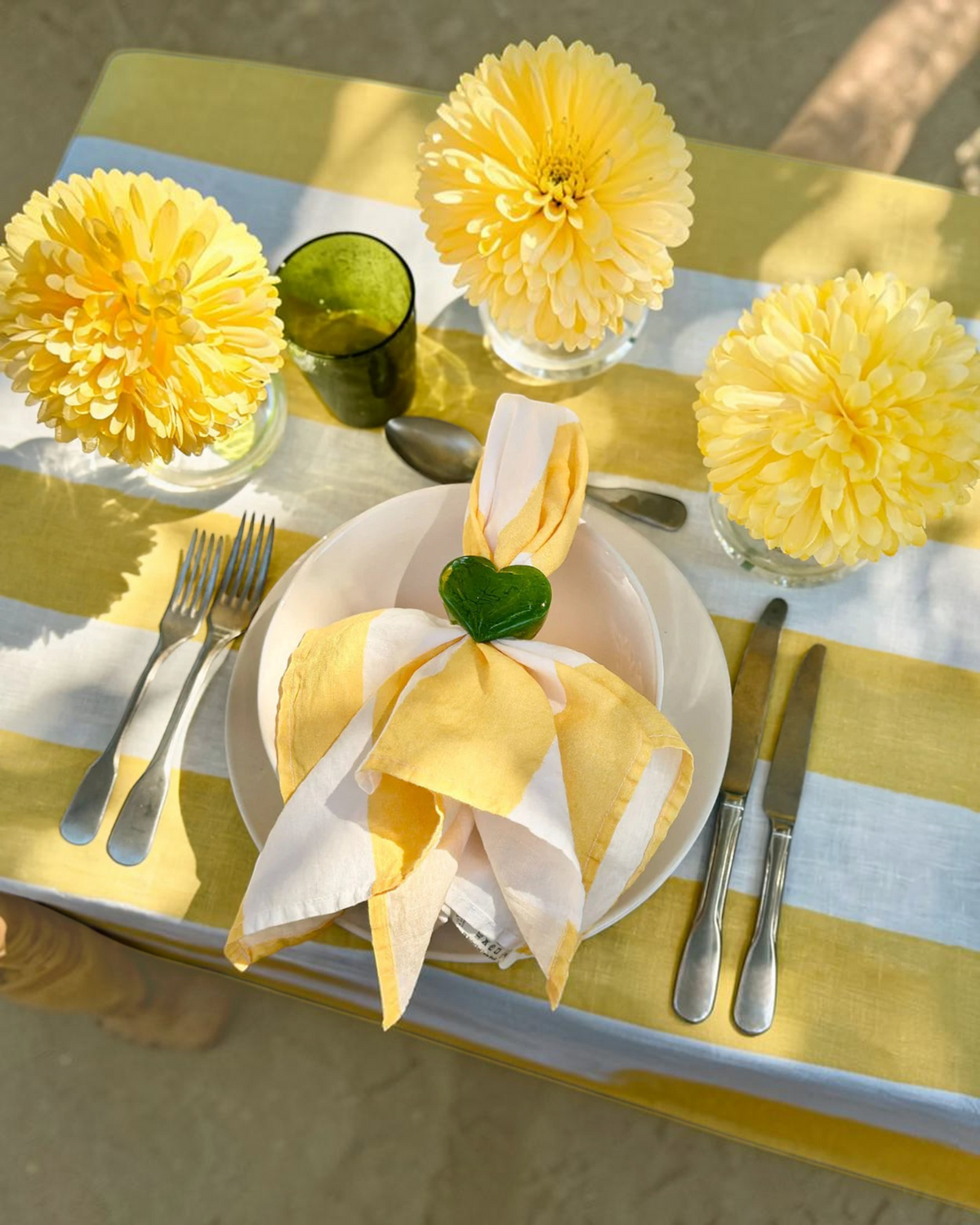 Birdie by Nina Liddle Design heart-shaped green resin napkin ring on a yellow and white striped table setting