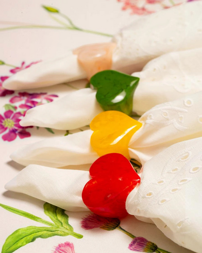 Birdie by Nina Liddle Design heart-shaped resin napkin rings in red, yellow, green, and peach on white napkins.