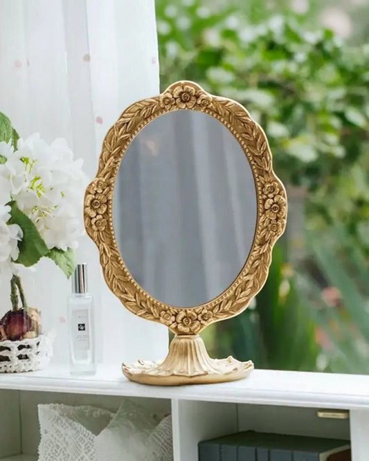 Birdie by Nina Liddle Design vintage oval makeup mirror with an ornate gold resin frame featuring floral details.