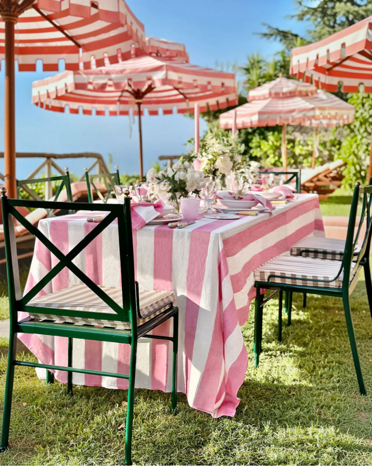 Birdie by Nina Liddle Design pink and white striped linen tablecloth on an outdoor dining table with matching napkins
